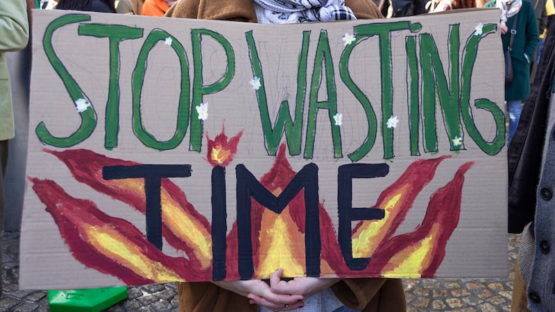 Protesters hold a banner that reads "stop wasting time" during a climate march.