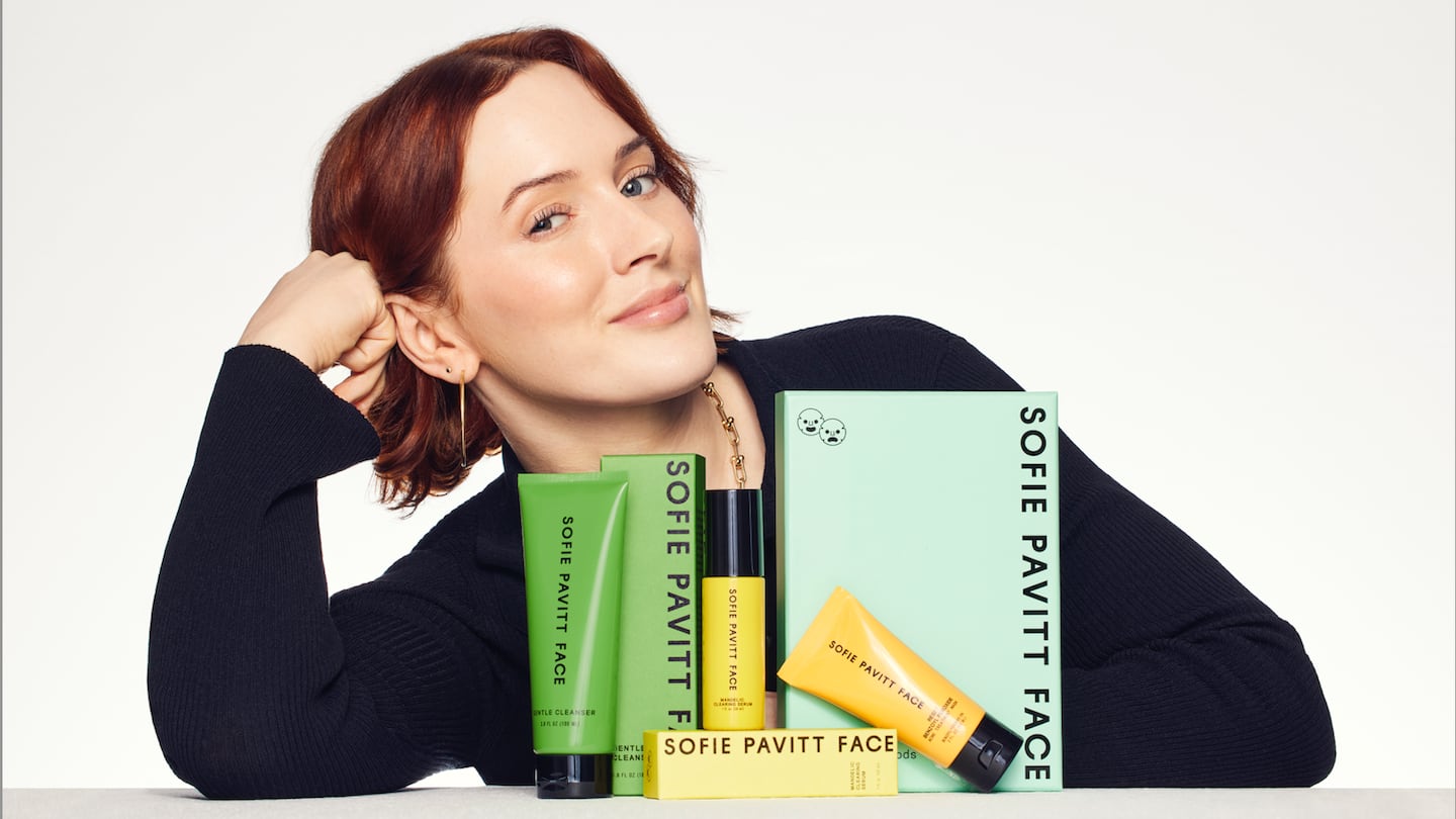 Sofie Pavitt posing with products from her skincare line Sofie Pavitt Face.