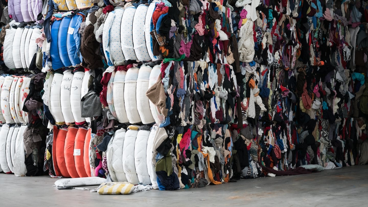 Bales of clothes are stacked in a warehouse.