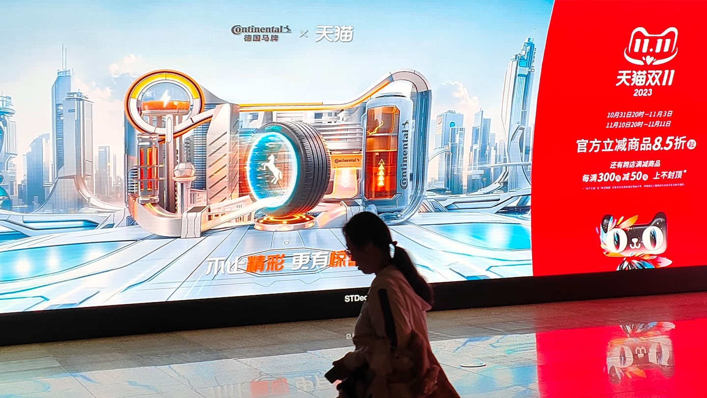 Citizens pass by the Double 11 shopping carnival promotional LCD screen displayed in a subway in Shanghai, China